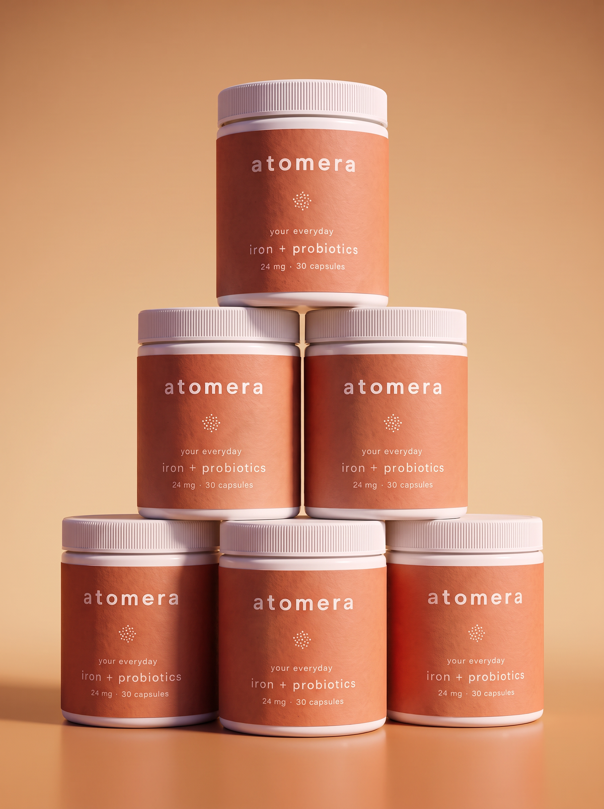 Six jars of atomera daily stacked in a pyramid on a warm peach background